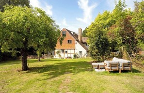 A house with a large lawn, a wooden fence, and a garden with outdoor furniture. - Luxurious 7 bed Tudor Country Retreat nestled in West Sussex woodland (Crawley)