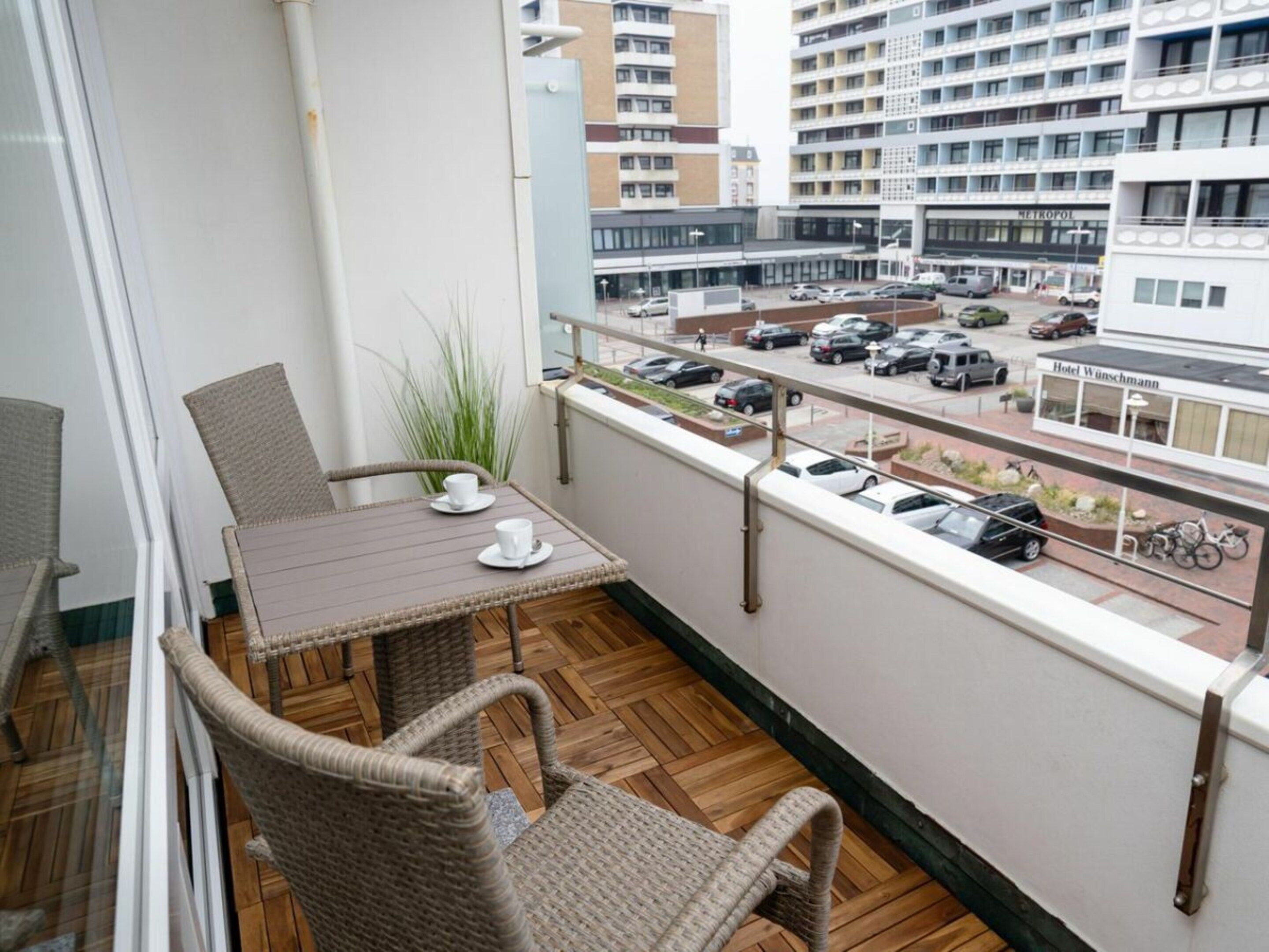 A balcony with wicker furniture, a table, and two cups.