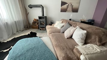 Ein gemütliches Wohnzimmer mit Sofa, Kissen, Teppich, Kamin und einem Bild an der Wand.