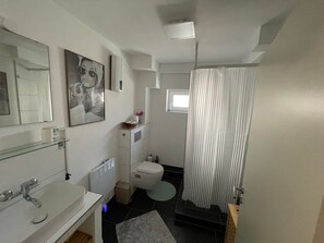 Ein modernes Badezimmer mit einer Glasablage, einer Toilette, einer Duschvorhang und einem kleinen Fenster.