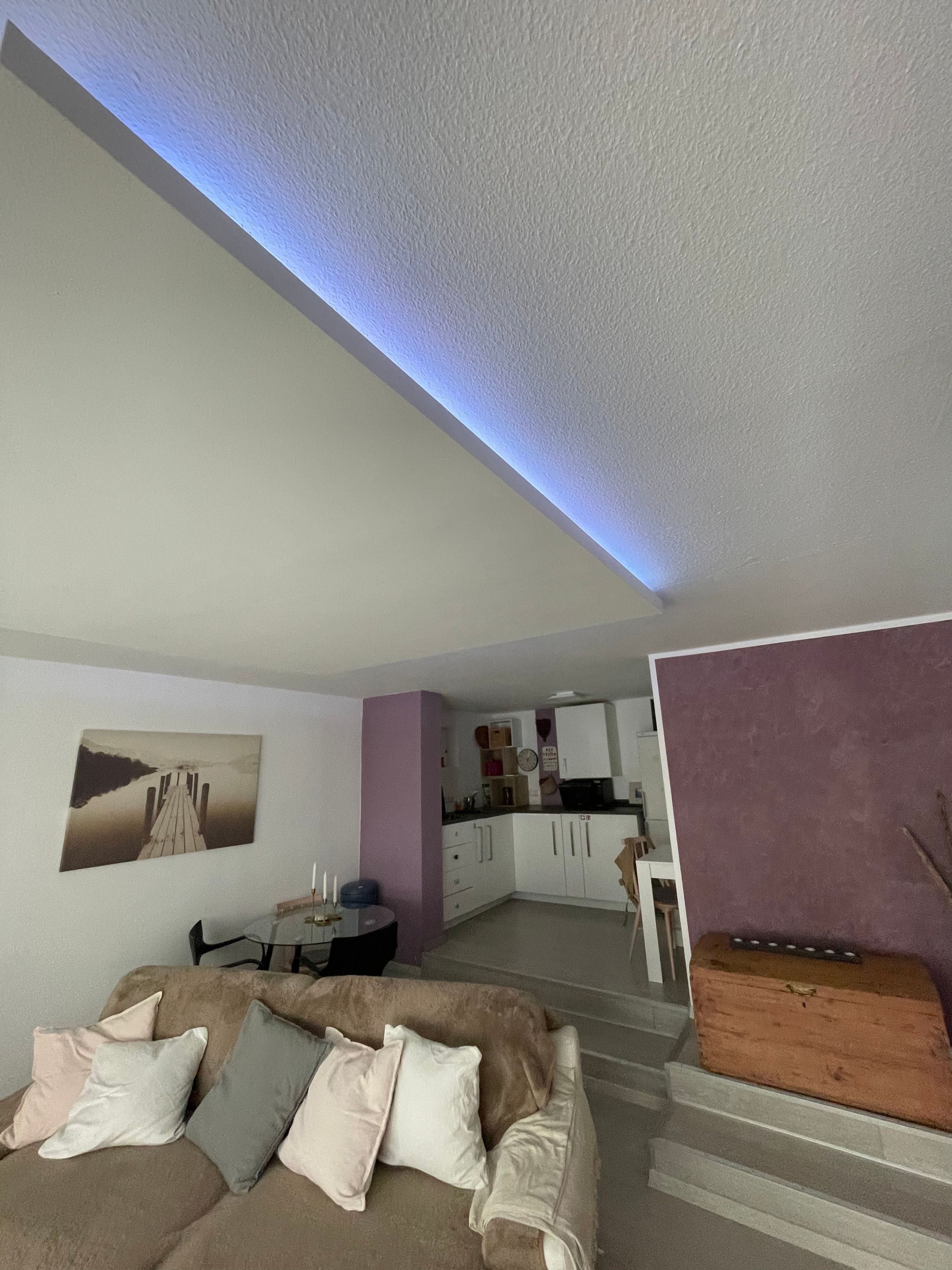 Ein modernes Wohnzimmer mit einer Couch, einem Esstisch und einer Küche im Hintergrund.