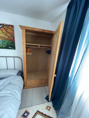 Ein Schlafzimmer mit einem Bett, einem Holzschrank und einem Bild an der Wand.
