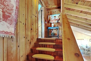 Un escalier en bois offrant une vue sur une pièce où se trouve un tableau représentant des animaux.