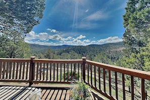Eine Holzterrasse mit Blick auf einen bewaldeten Gebirgszug.