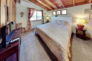 Ein Schlafzimmer mit Bett, Schreibtisch, Stuhl, einem Fenster mit Vorhängen und einer Lampe.