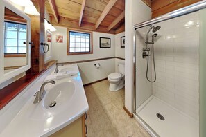 Ein Badezimmer mit weißem Waschbecken, einer Toilette und einer Dusche.