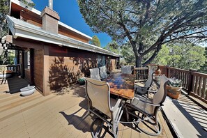 Eine Terrasse mit Esstisch und Stühlen, umgeben von einer Holzterrasse und einem großen Baum.