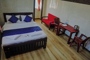 Une chambre d’hôtel avec un lit, un canapé rouge, une table en bois et une chaise.