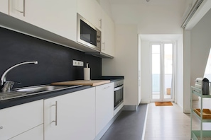 A modern kitchen with a black countertop, stainless steel appliances, and a view to the outside. - NEW! Rooftop Charm Lisbon Retreat (Lisbon)