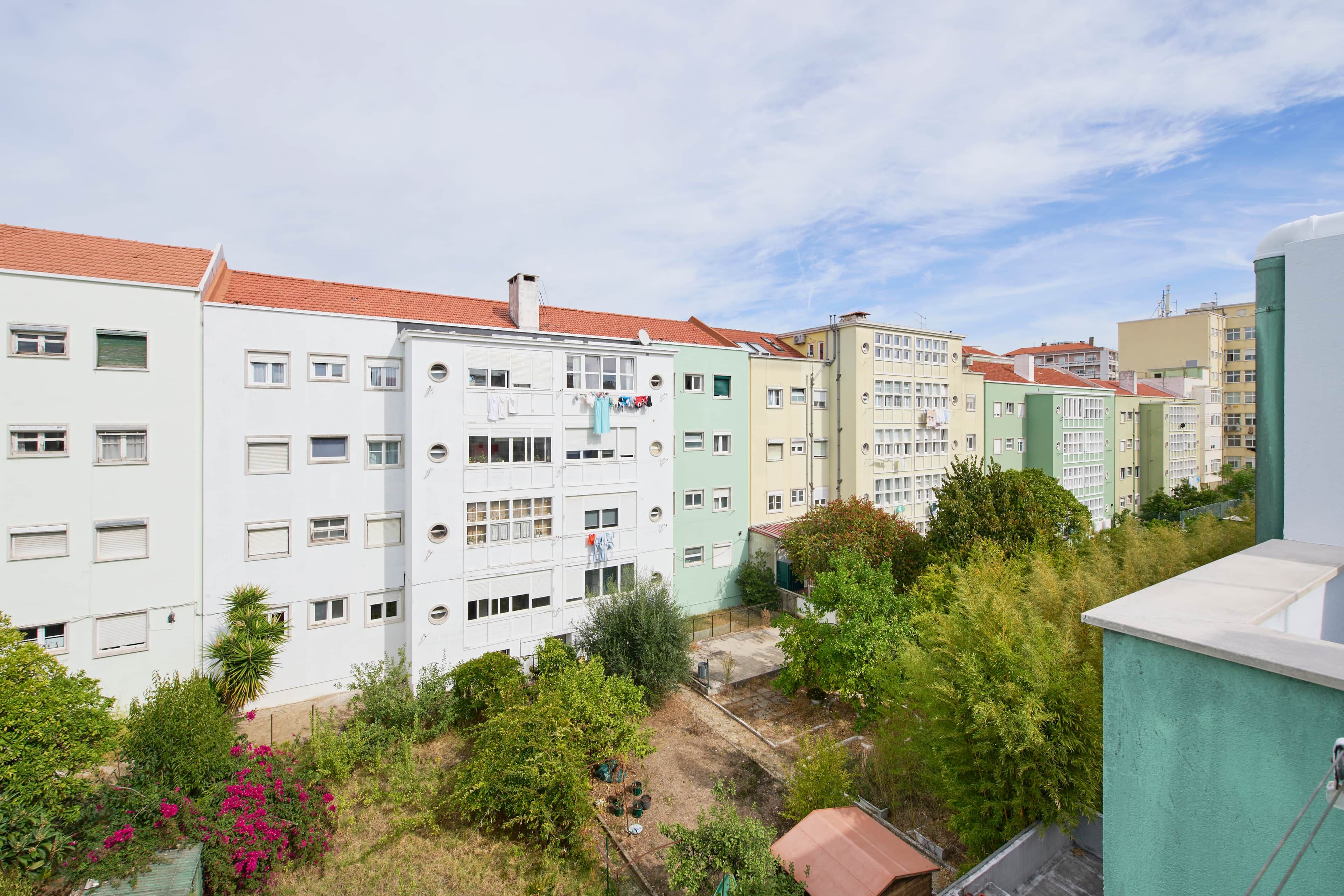 Una hilera de edificios residenciales de varios pisos con balcones, rodeados de vegetación y árboles.