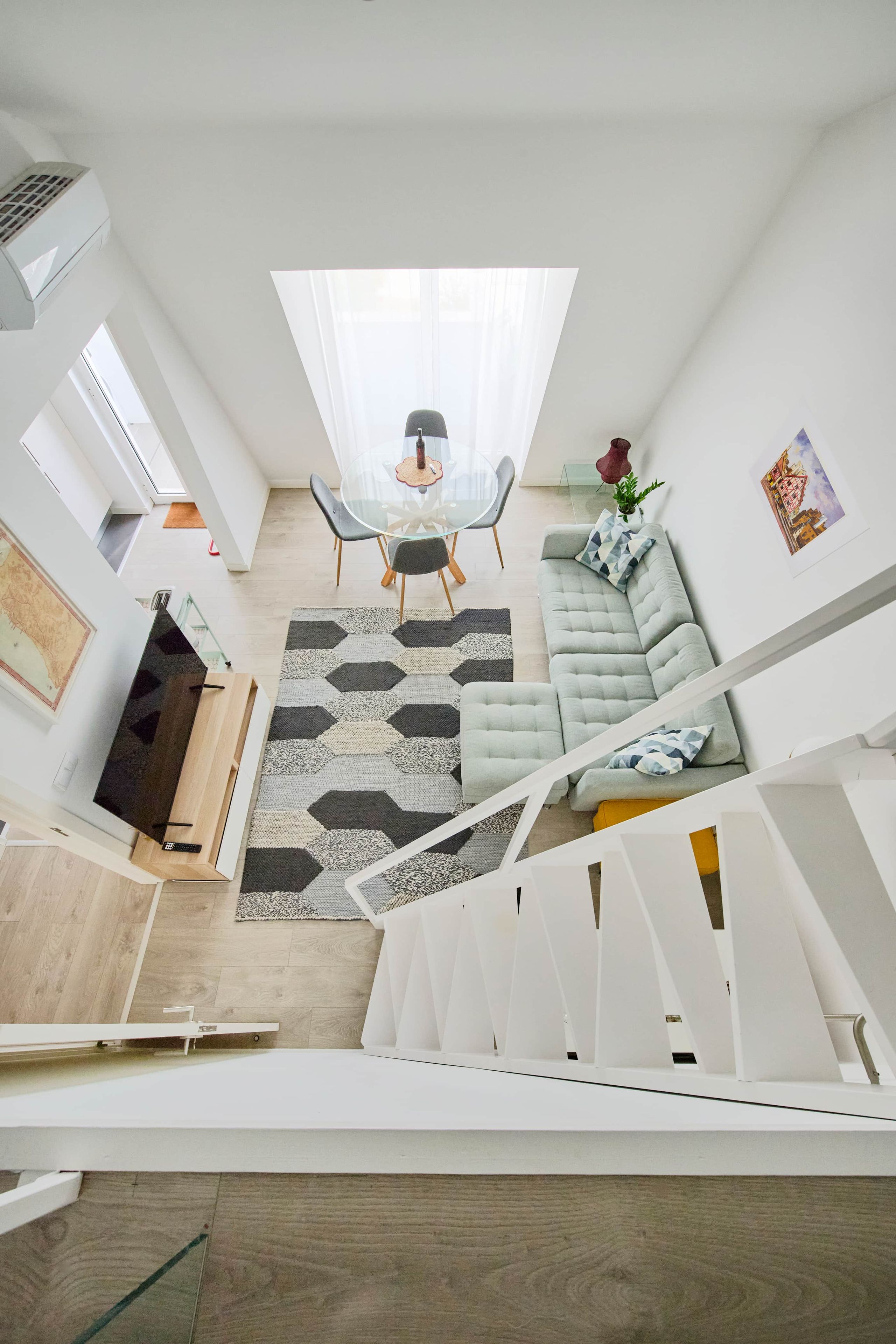 A modern living space with a dining area, a sofa, and a staircase.