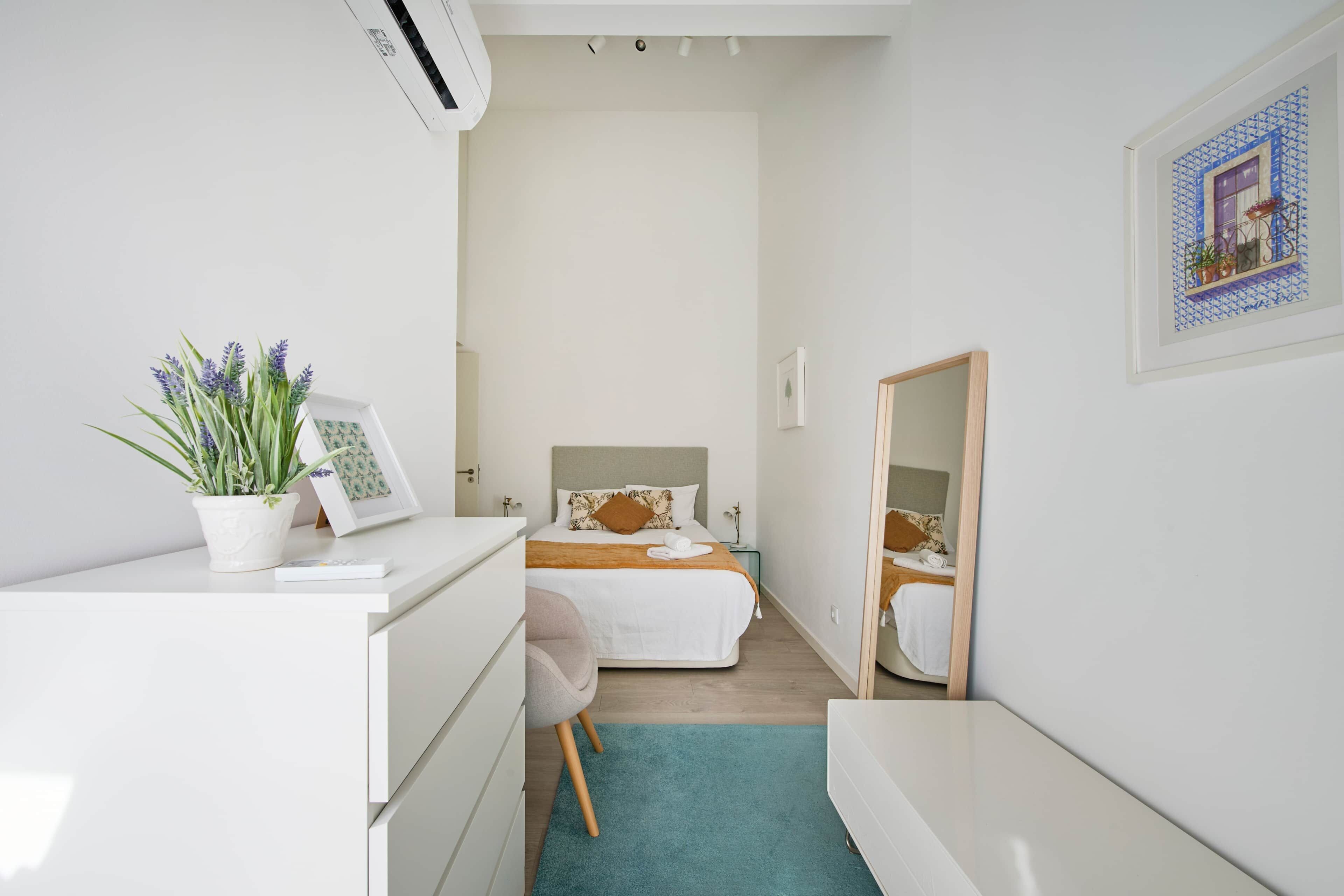 Un dormitorio moderno con cama, mesita de noche y espejo.
