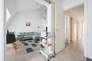 A modern living room with a sofa, a dining table, and a kitchen area with a cart. - NEW! Rooftop Charm Lisbon Retreat (Lisbon)