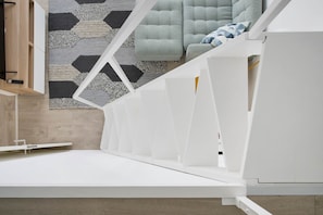 A modern, minimalist room with a white bed frame, a geometric-patterned rug, and a light-colored sofa. - NEW! Rooftop Charm Lisbon Retreat (Lisbon)