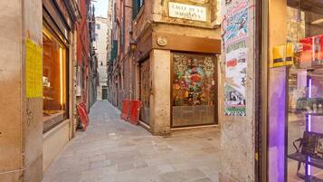 A narrow street with a shop on the right and a building with a sign reading 'Calle De La Madona.'