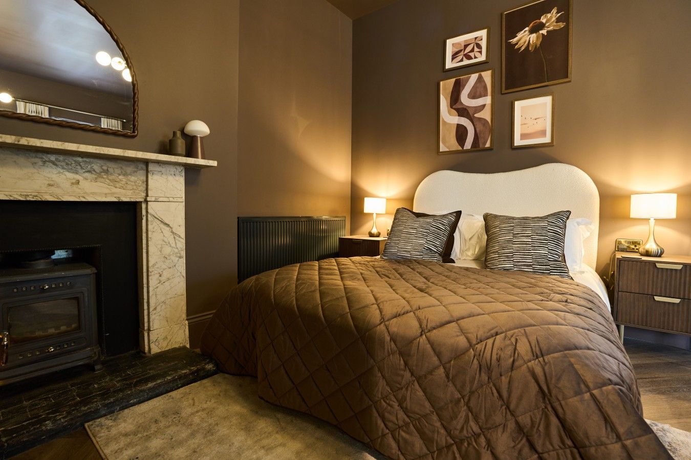 Una habitación de hotel con una cama grande, una chimenea y obras de arte en las paredes.