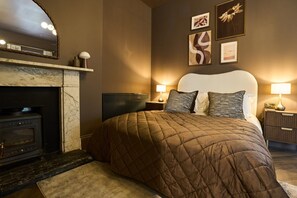 Una habitación de hotel con una cama grande, una chimenea y obras de arte en las paredes.