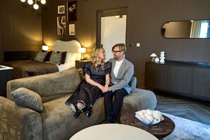 A modern living room with a sofa, a dining table with a bowl of cookies, and a bed in the background. - *NEW* Large Luxury Garden Terrace Suite in South Downs (Warningcamp)