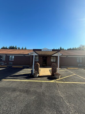 En byggnad med en skylt som visar ”INGÅNG 2” och en överbyggd entré med krukväxter.