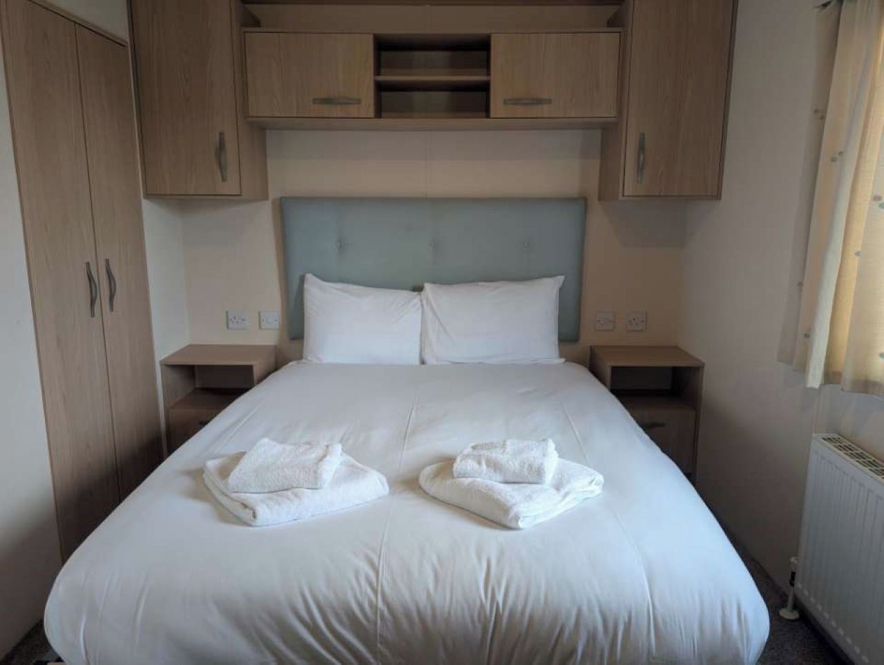 Ett hotellrum med en stor säng, två sängbord och träskåp ovanför sängen.