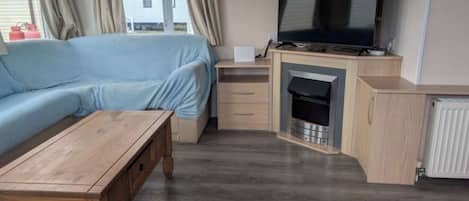 A compact living space with a sofa, a wooden table, a television, and a fireplace.