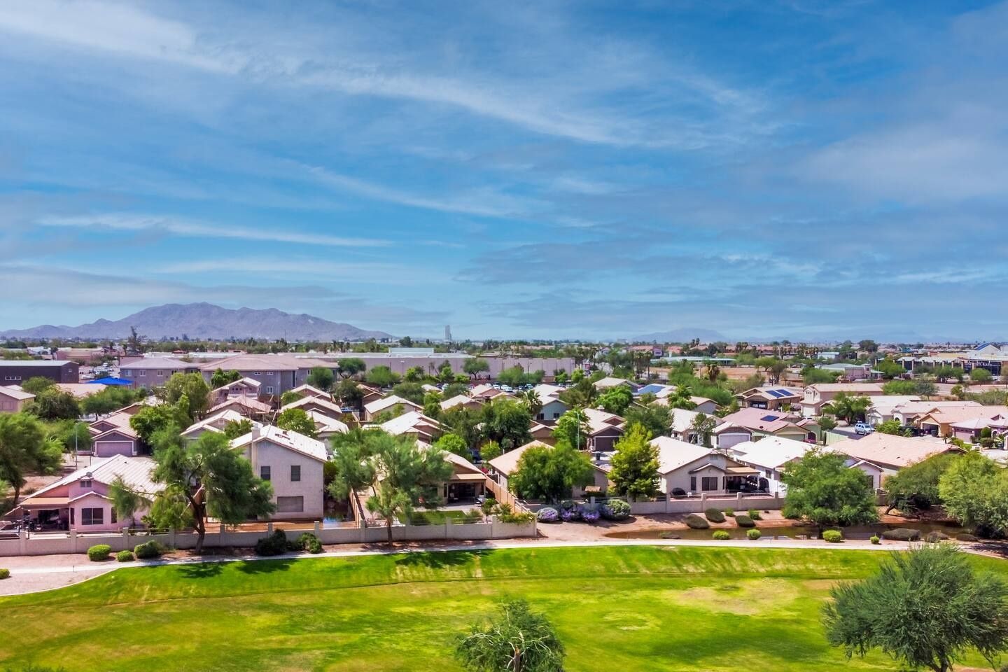 A residential area with houses, green lawns, and a mountain in the background.