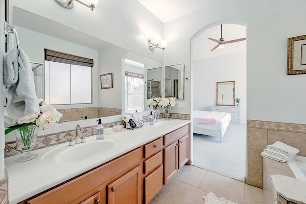 A modern bathroom with a double sink vanity, a large mirror, and a ceiling fan.