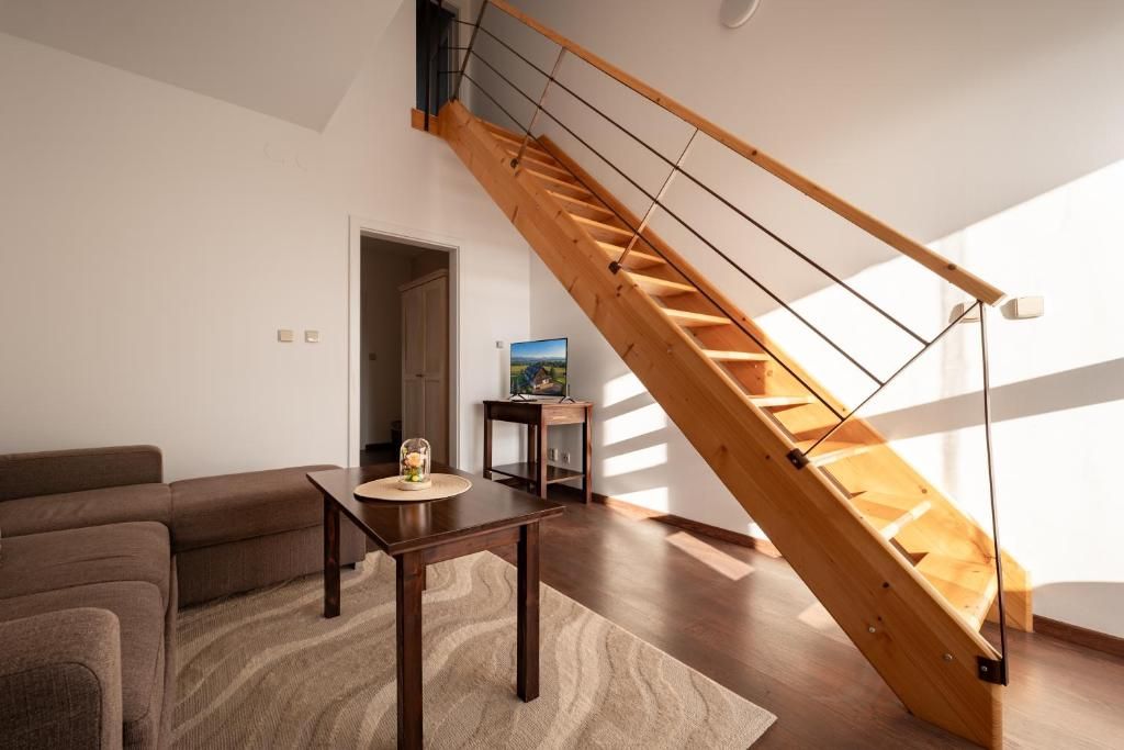 A modern living room with a wooden staircase, a sofa, a coffee table, and a television.