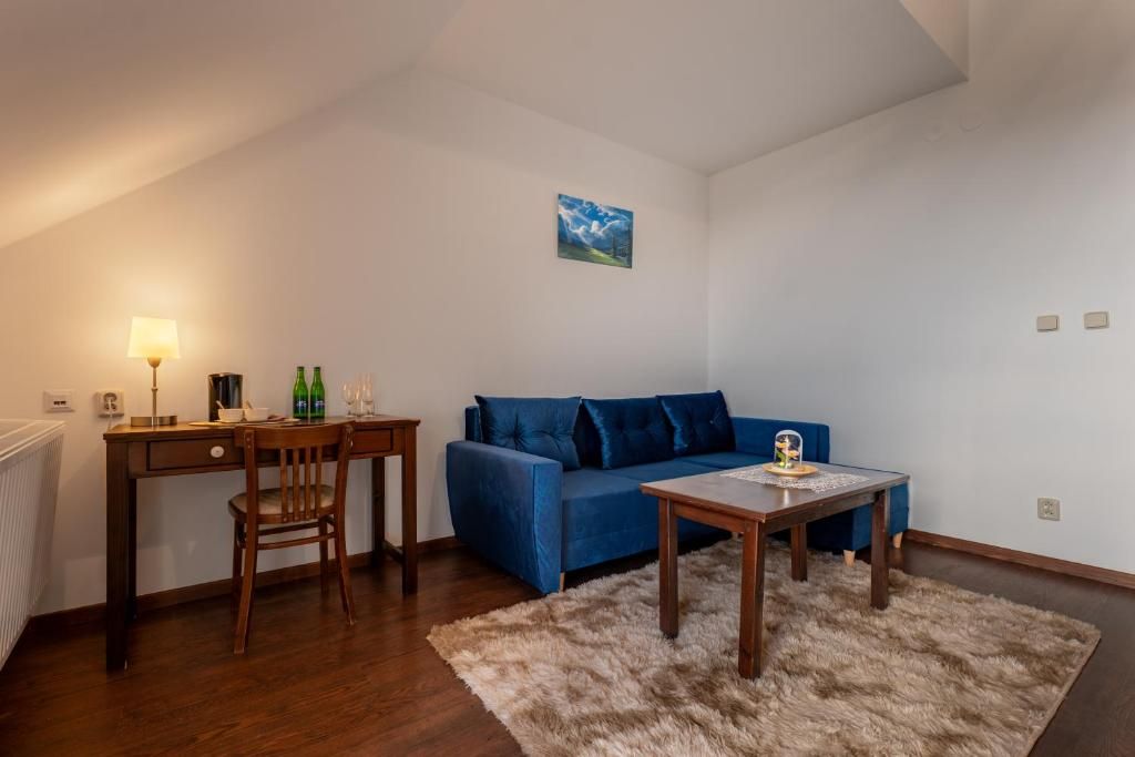Una sala de estar con un sofá azul, una mesa de centro de madera, una lámpara y un cuadro en la pared.
