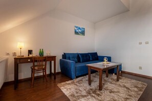 A living room with a blue sofa, a wooden coffee table, a lamp, and a painting on the wall. - Serenity Residence Hotel & Wellness (LIPTOVSKÝ TRNOVEC)