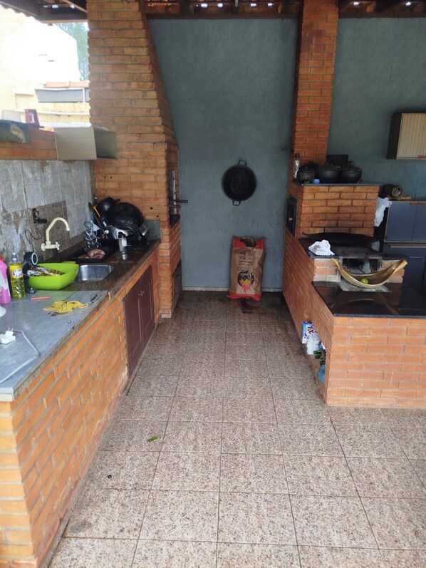 A compact kitchen with a brick backsplash, a sink, and a hanging pot rack.