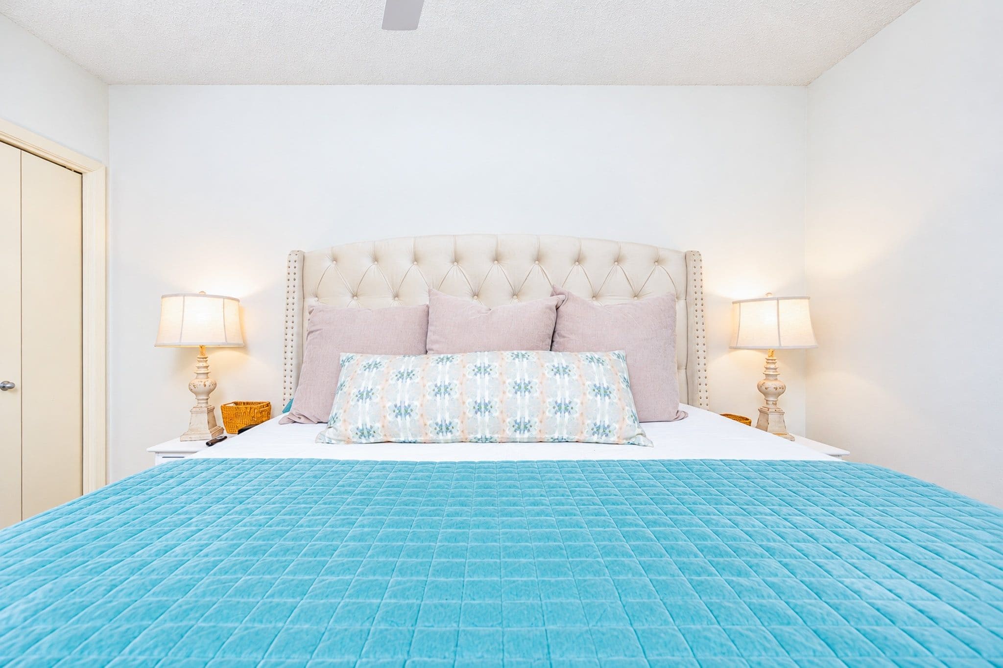 Een slaapkamer met een groot bed, twee bedlampen en een deur.