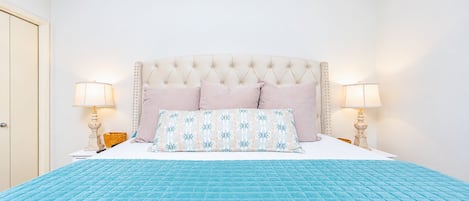 A bedroom with a large bed, two bedside lamps, and a door.