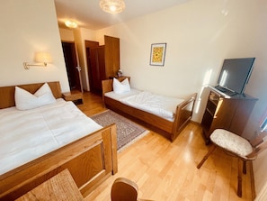 Ein Hotelzimmer mit zwei Betten, einem Fernseher und einem Schreibtisch.