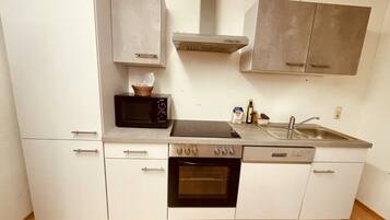 A compact kitchen with a microwave, oven, sink, and cabinets.