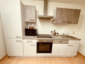 Eine kleine Küche mit Mikrowelle, Backofen, Spüle und Schränken.