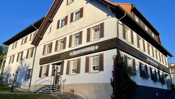 Un immeuble à plusieurs étages, sur lequel on peut lire une enseigne indiquant qu’il s’agit d’une maison d’hôtes ou d’une auberge.