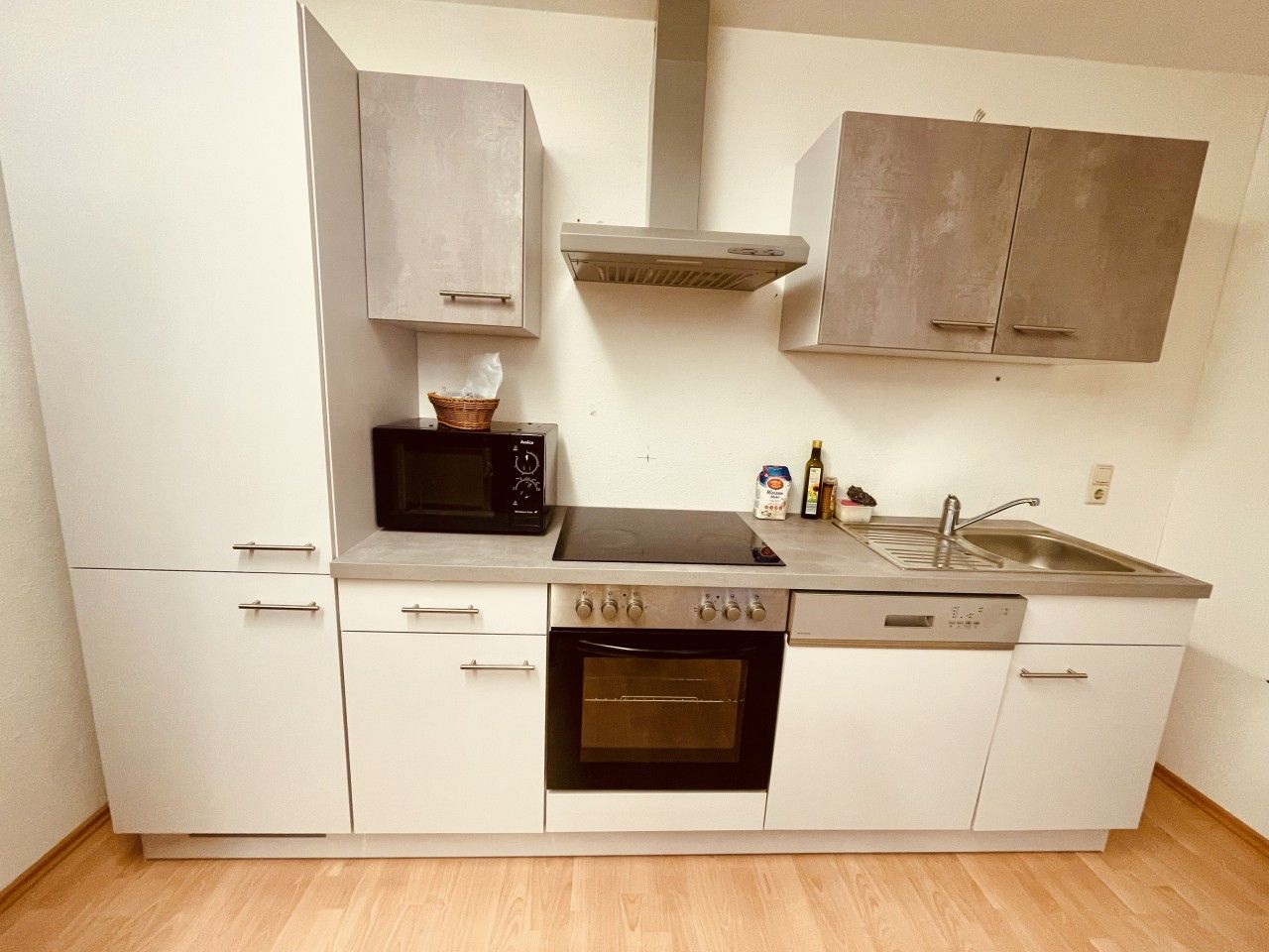 Eine kleine Küche mit Mikrowelle, Backofen, Spüle und Schränken.