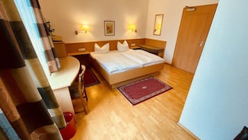 Une chambre d’hôtel avec un lit, des tables de chevet, un bureau et une chaise.