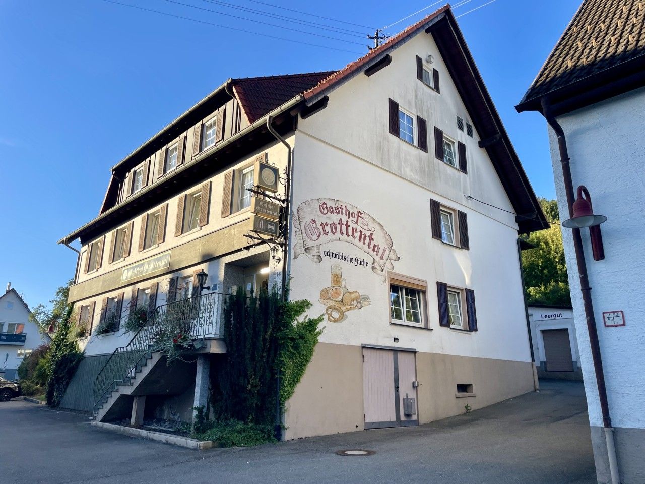 Un bâtiment à deux étages, avec une enseigne indiquant « Gasthof Grotenthal » et un escalier menant à l’entrée.