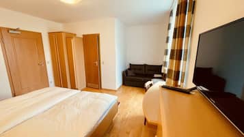 Una habitación de hotel con una cama, un escritorio con computadora, un televisor y un sofá.
