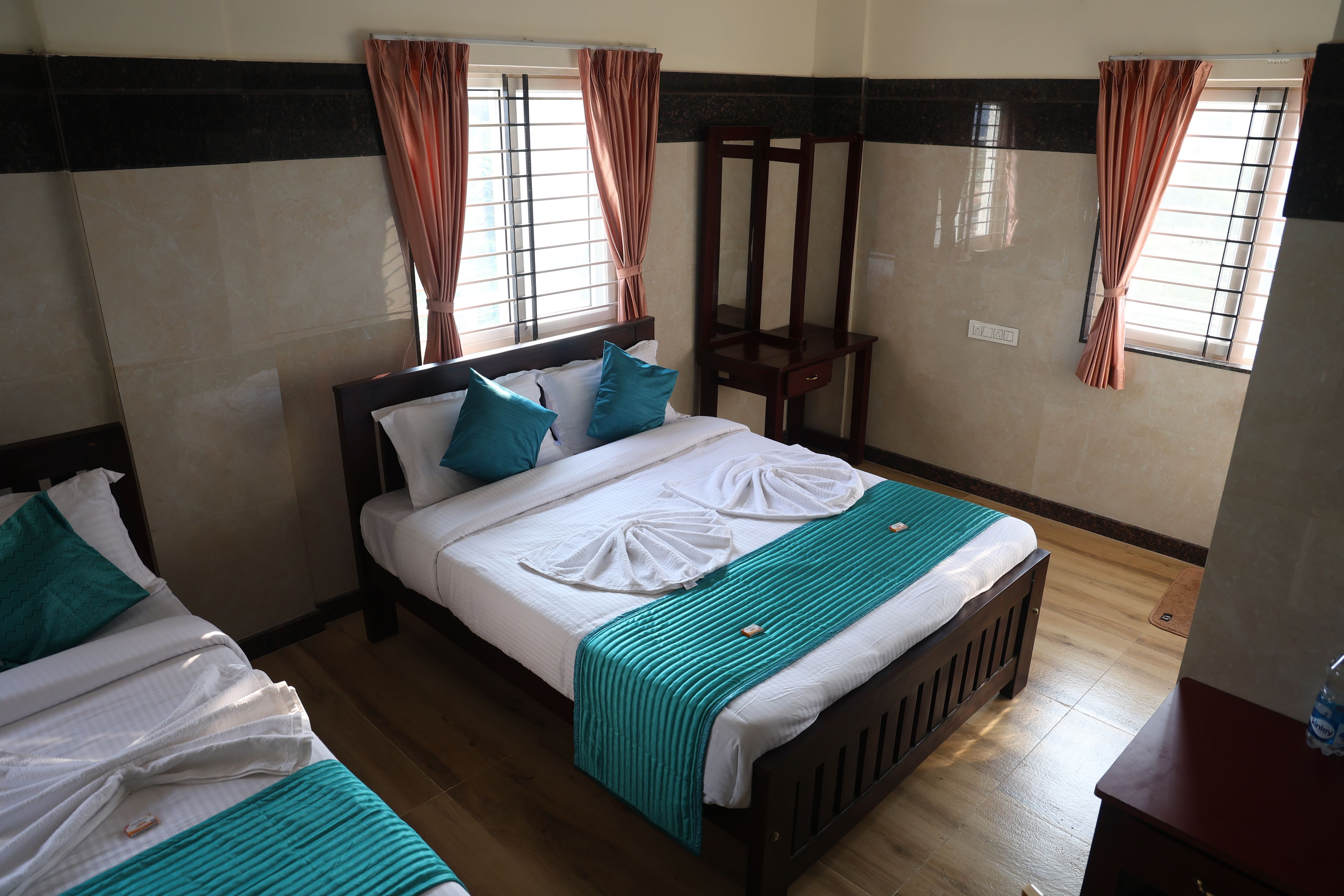 A hotel room with a bed, a chair, and a window with curtains.