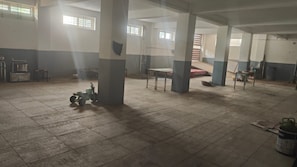 A spacious indoor area with tiled flooring, large pillars, and a high ceiling. - Anugraha Lodge (Ramanagara)
