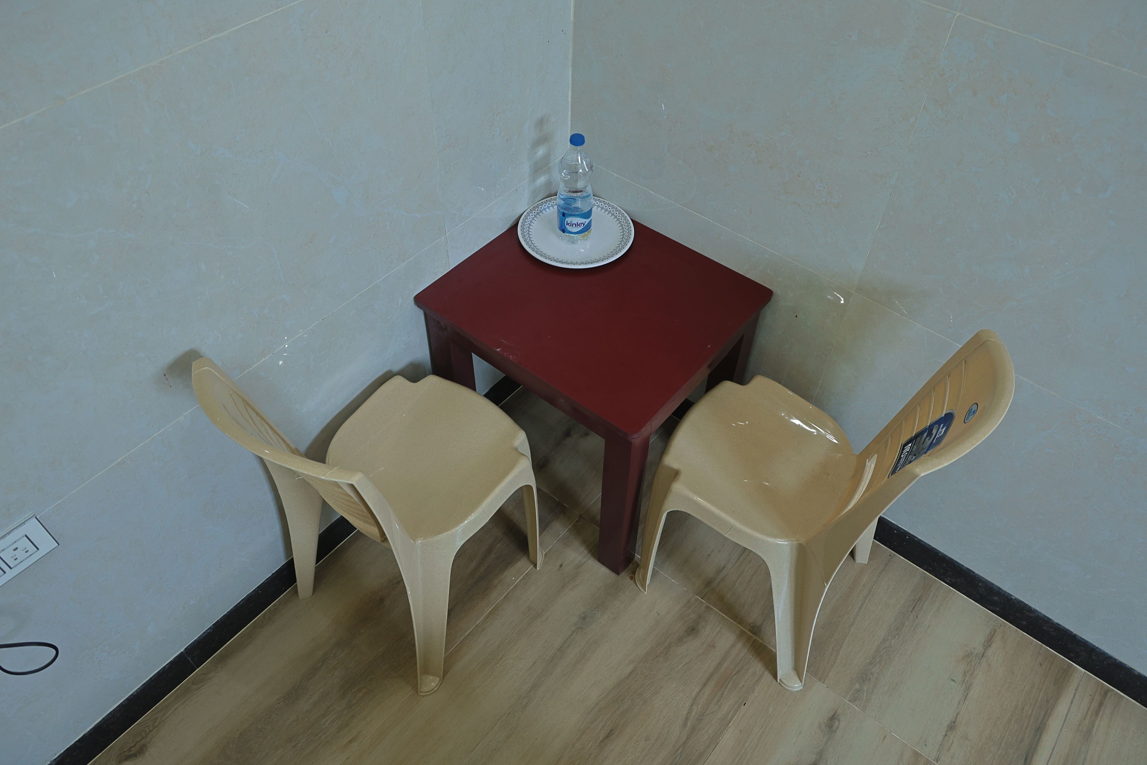 A small room with a red table and two beige chairs. There is a water bottle on the table.