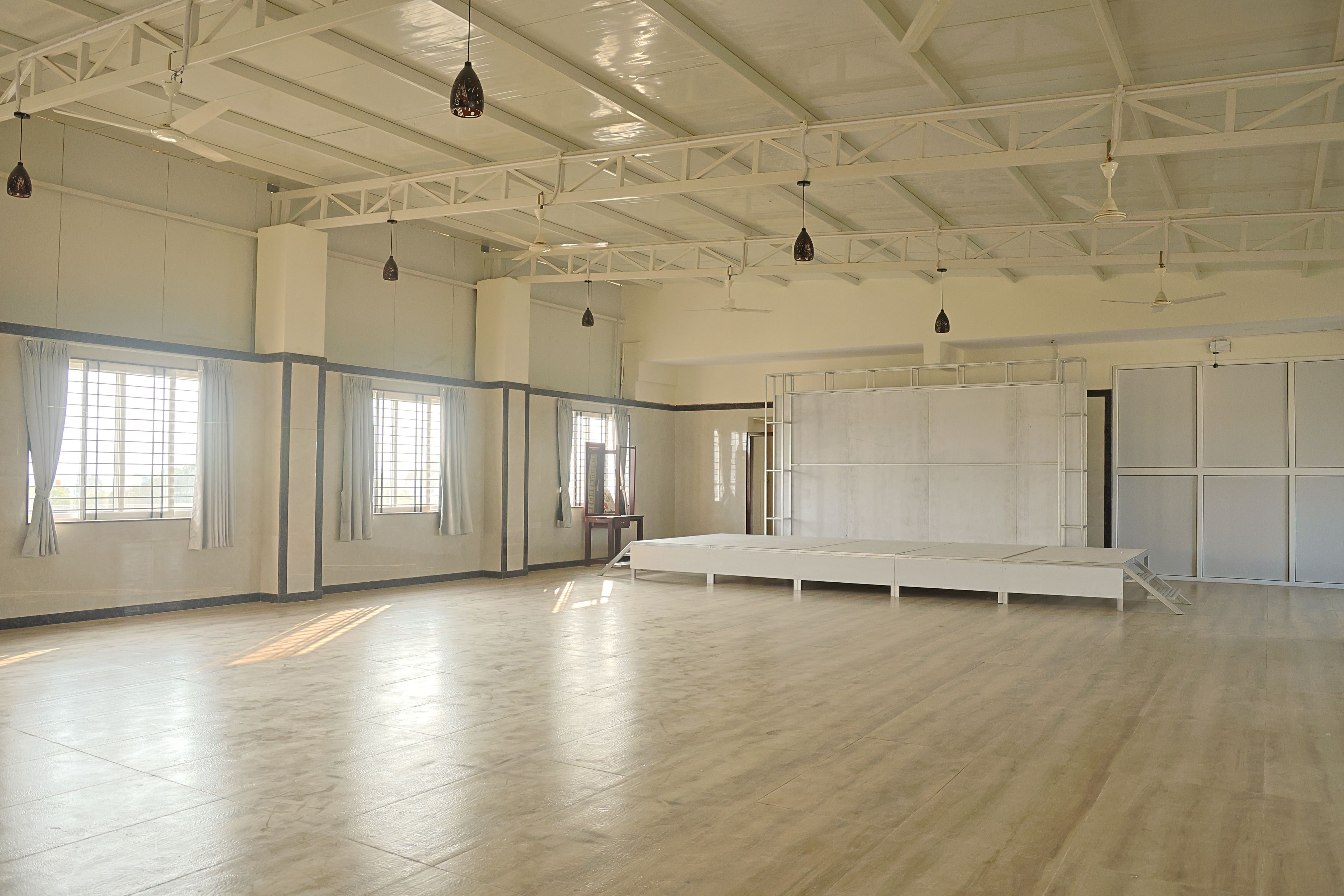 A spacious room with high ceilings, large windows, and a central area with a platform.