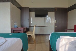Ein Hotelzimmer mit zwei Betten, einem Schreibtisch, einem Stuhl, einem Fernseher und einem Kleiderschrank.