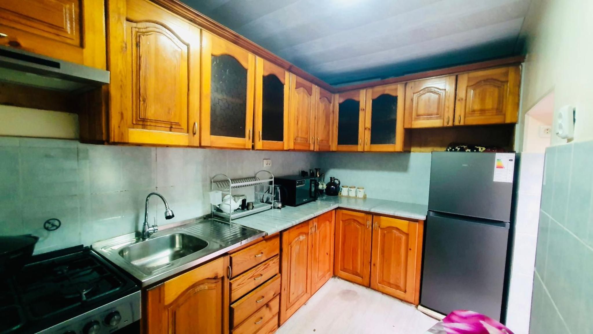 A kitchen with wooden cabinets, a stainless steel sink, a stove, and a refrigerator.