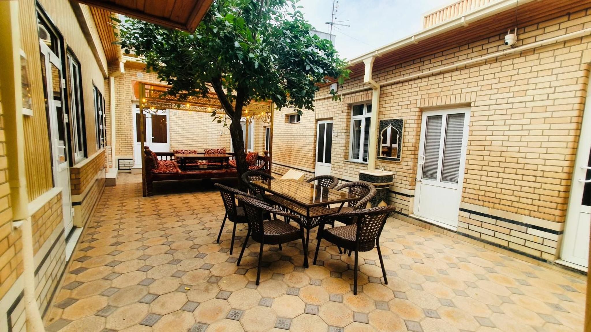 A courtyard with a table and chairs, a bench, and a tree.