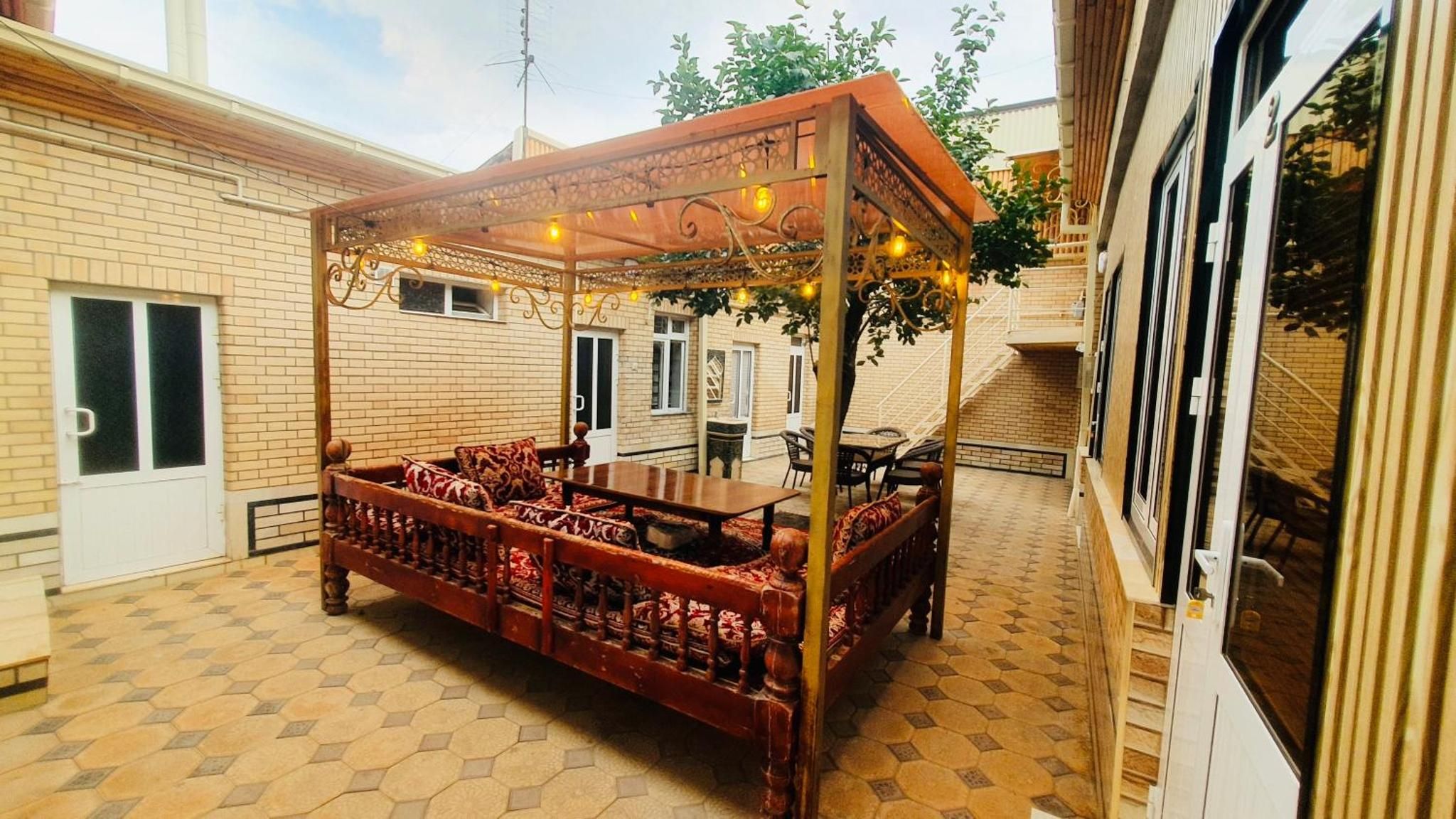 Un espacio al aire libre cubierto con un banco y una mesa de madera, rodeado de paredes de ladrillo y un piso de baldosas.