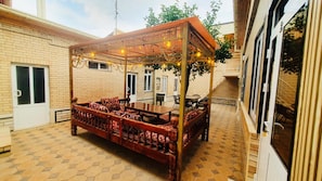 Un espacio al aire libre cubierto con un banco y una mesa de madera, rodeado de paredes de ladrillo y un piso de baldosas.